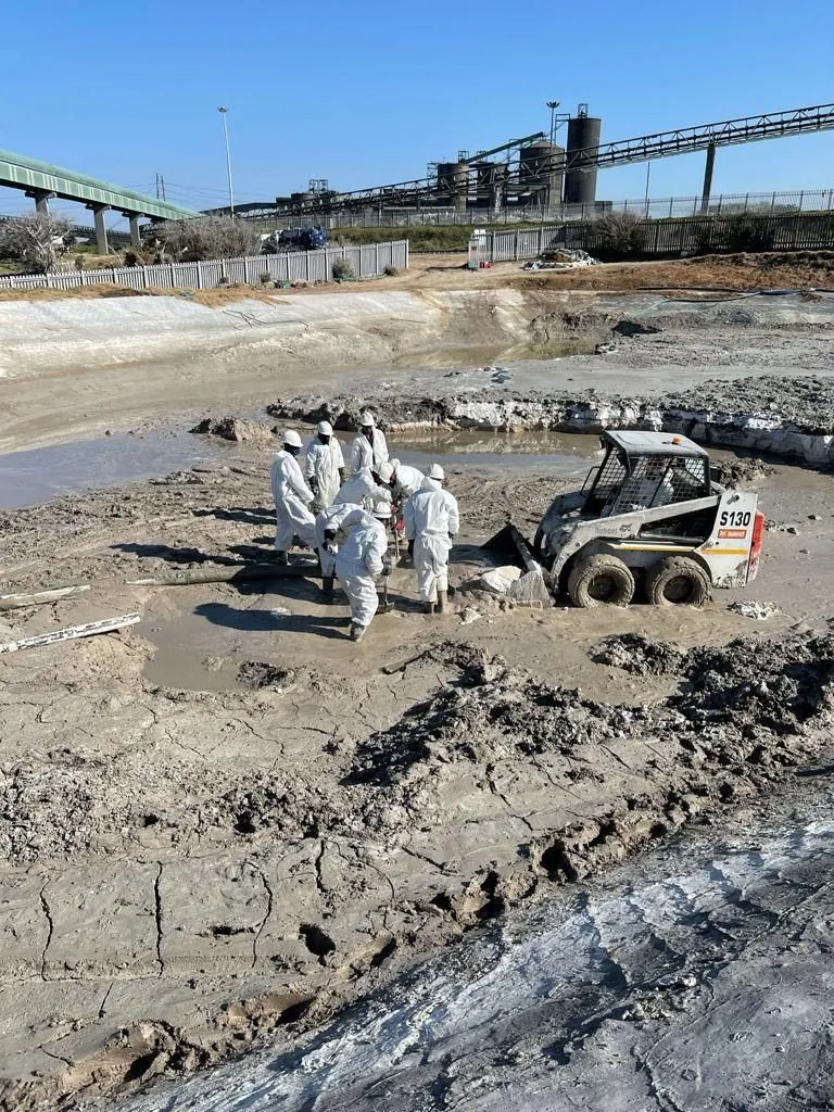 Crew in PPE working with a Bobcat S130 in mud